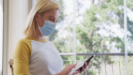 Woman-wearing-face-mask-wiping-her-smartphone-with-a-tissue