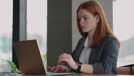 contable o gerente de relaciones públicas de una gran empresa está trabajando en la oficina y durante el día joven mujer seria está viendo información en la computadora portátil