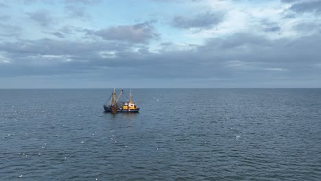 Vuelo-Por-Drone-De-Un-Barco-De-Pescadores-Arrastrando-Las-Redes-A-Través-Del-Agua-De-La-Costa-De-Ameland