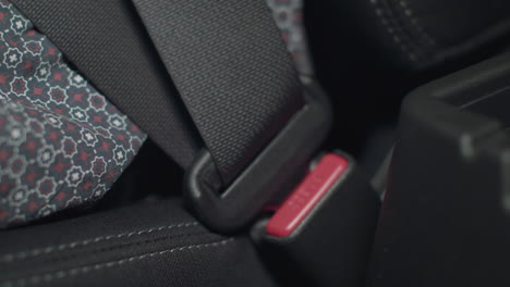 Close-up-of-a-woman-buckling-a-seat-belt-inside-a-car-with-black-interior