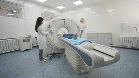 female patient is undergoing ct or mri scan under supervision of two qualified radiologists in modern medical clinic. patient lying on a ct or mri scan table, leaves the machine