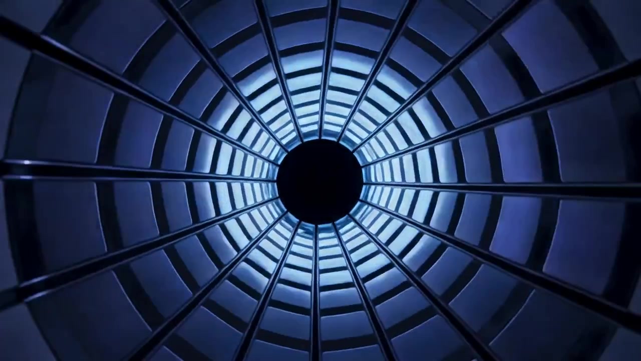 Câmera em movimento revelando um túnel circular canelado centralizado, com anéis luminosos giratórios e nervuras radiais de metal.