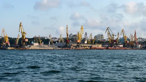 Grúas-De-Doble-Pluma-En-El-Puerto-De-Odesa-Con-Un-Montón-De-Arena-De-Un-Barco-Que-Navega-En-El-Mar-Negro