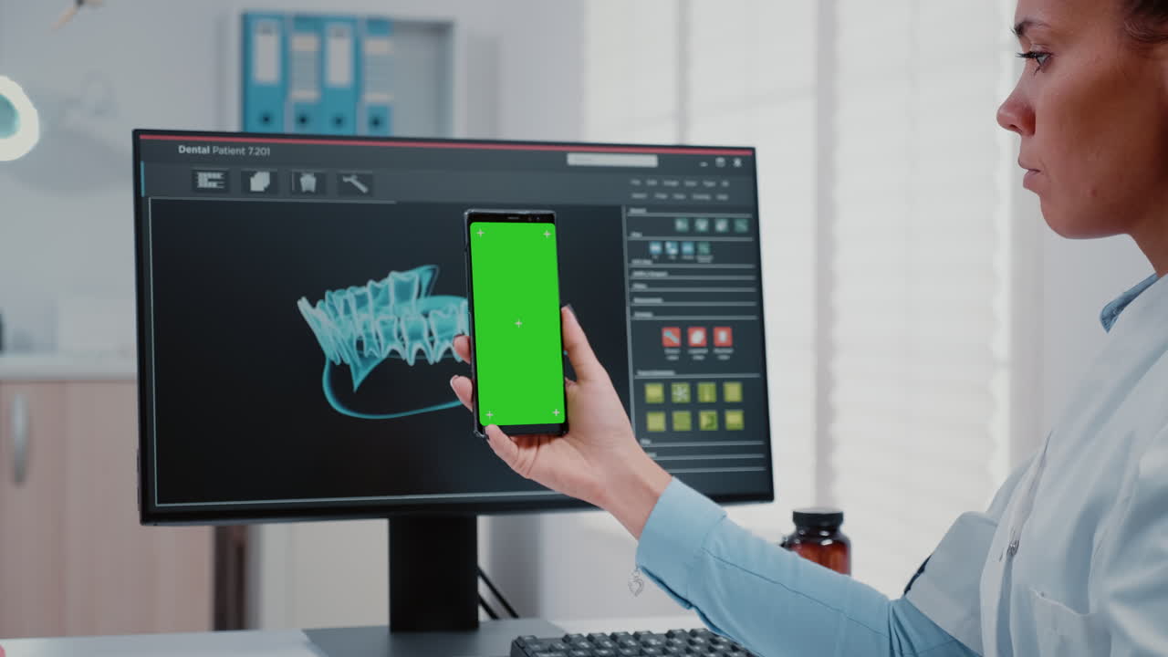 Stomatologist vertically holding green screen on mobile phone