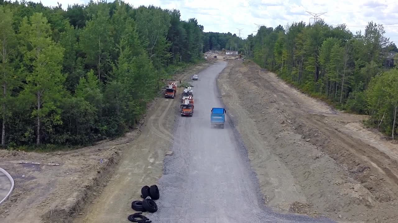 Aerial following a truck along a road that is being built