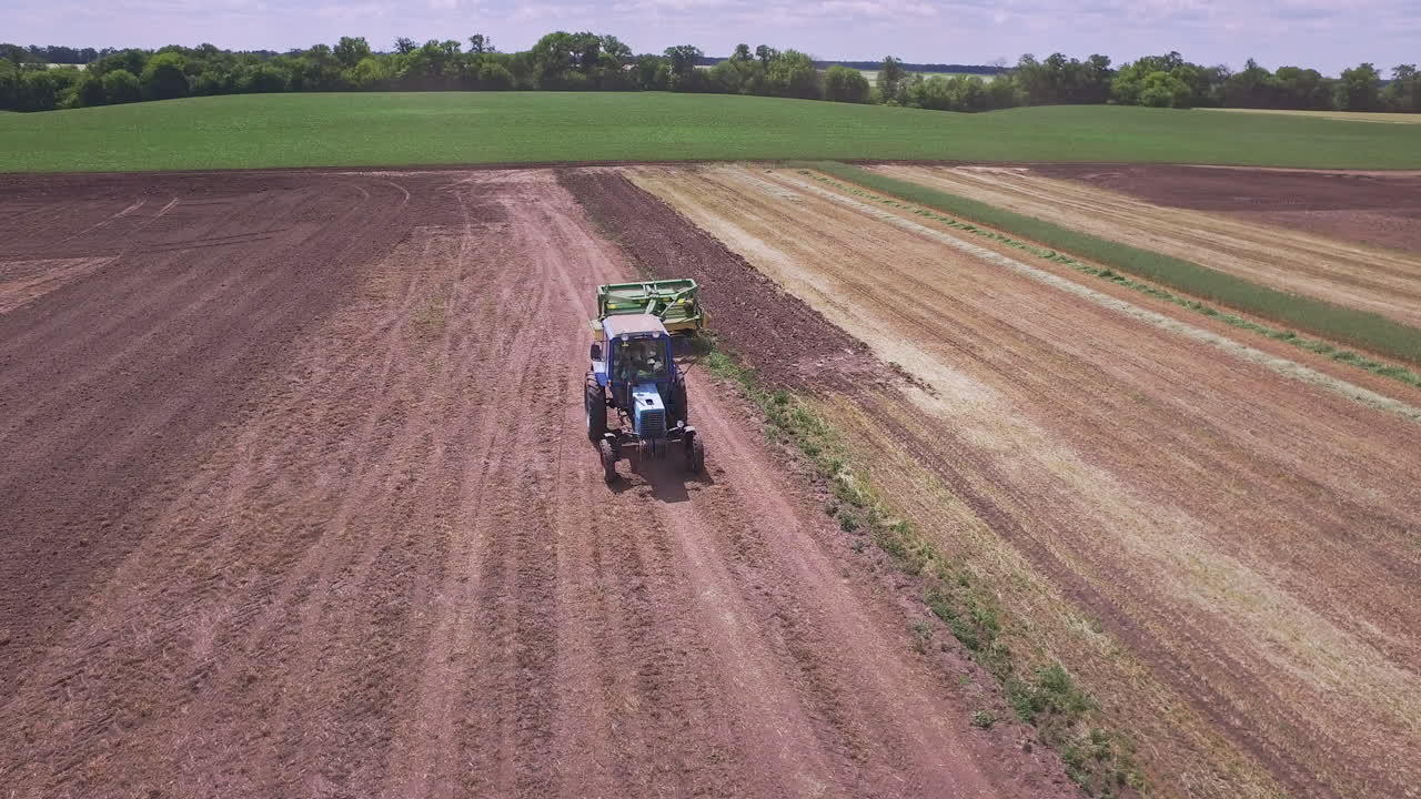농업용 트랙터와 트레일러를 가지고 경작지에서 일하는 경작용 트랙터