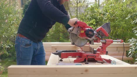 the man is starting to saw the wood with a circular saw