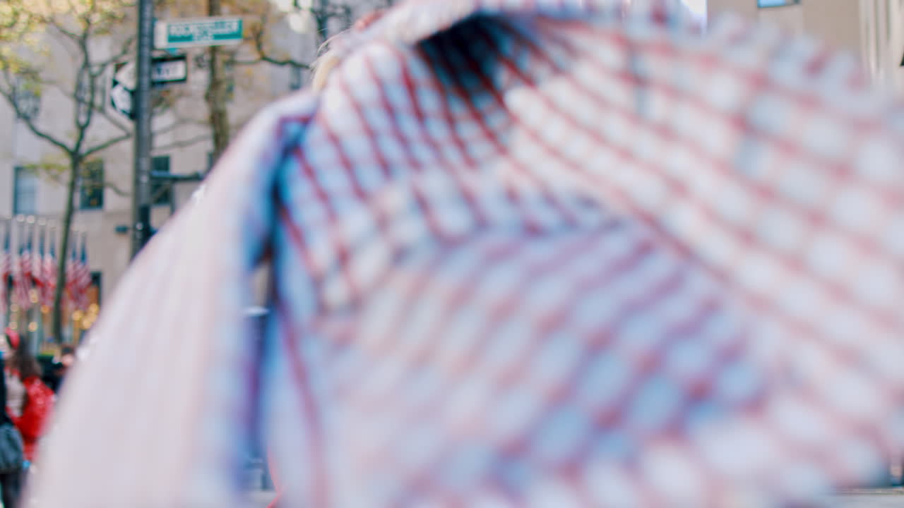 New York, USA, 5. oktober 2025: Kvinde i rød rullekrave holder jakke på bygade. Kvinde i rød rullekrave holder en ternet blazer, mens hun står på et fortov i New York.