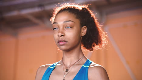 close up of a focused young sportswoman warming up and stretching legs in indoor sport facility