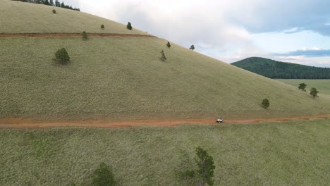 vista panorámica de la exuberante colina en el pico de los verdes, arizona con vehículo en el camino en un día nublado - drone aéreo