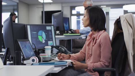 woman taking notes while sitting on her desk at home