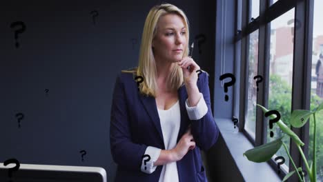 Animation-of-question-marks-over-caucasian-businesswoman-working-at-office