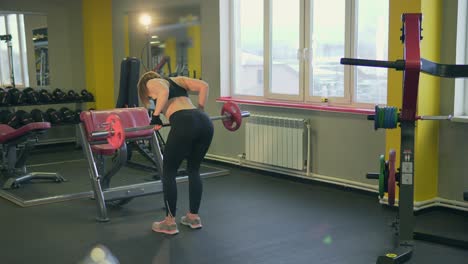 woman performing barbell deadlift in a gym