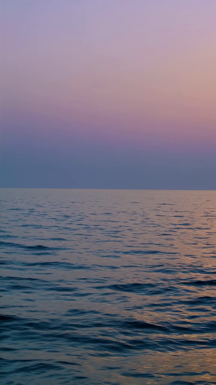Serene ocean sunset with gentle waves, captured from a low-angle perspective