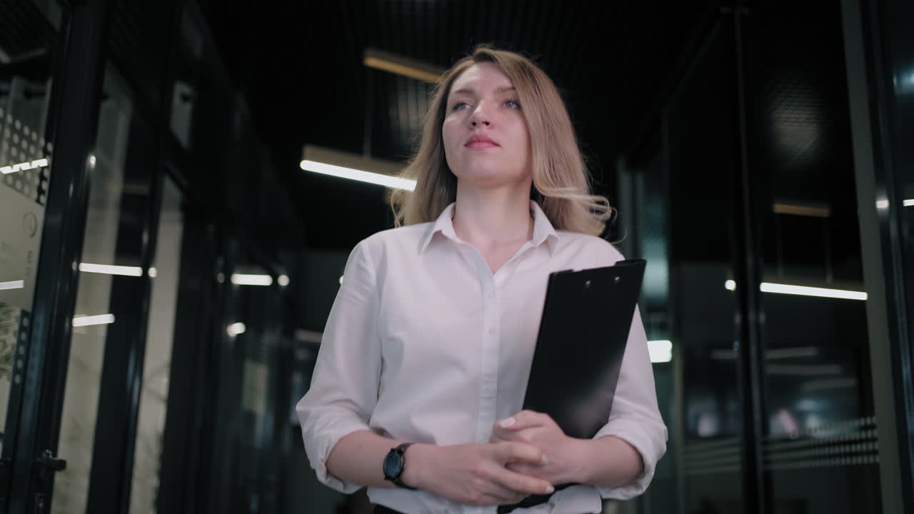 Beautiful business woman walking in office corridor. Businesswoman walking on meeting in office interior. Cheerful professional going on meetup in business center hallway