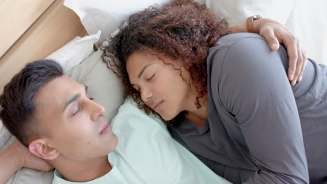una pareja de hombres homosexuales felices y diversos acostados en la cama durmiendo abrazándose en casa, en cámara lenta.