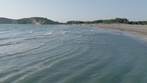 Sea-waves-in-slow-motion-on-a-beach-with-people-walking-close-by