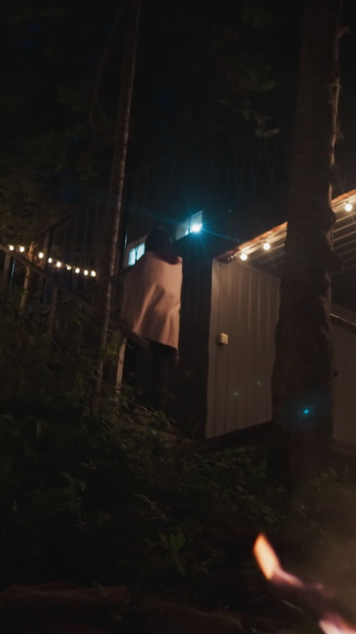joven sube la escalera en el patio. territorio aislado perteneciente a un retiro rural para viajeros en la densa extensión de bosque. fogata crepitante