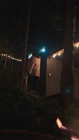 joven sube la escalera en el patio. territorio aislado perteneciente a un retiro rural para viajeros en la densa extensión de bosque. fogata crepitante