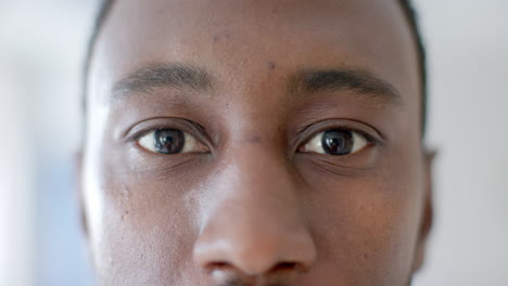 portrait close up of eyes of african american male doctor smiling in hospital ward, slow motion