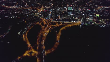 Luftdrohne-Von-Perth-City-Westaustralien-Bei-Nacht,-Die-Die-Dynamische-Natur-Der-Stadt-Durch-Die-Autobahn-Zeigt,-Die-In-Die-Stadt-Einfährt