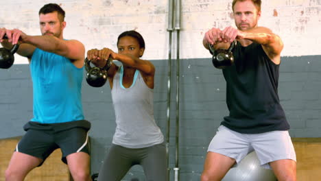 fit people lifting kettlebells in gym