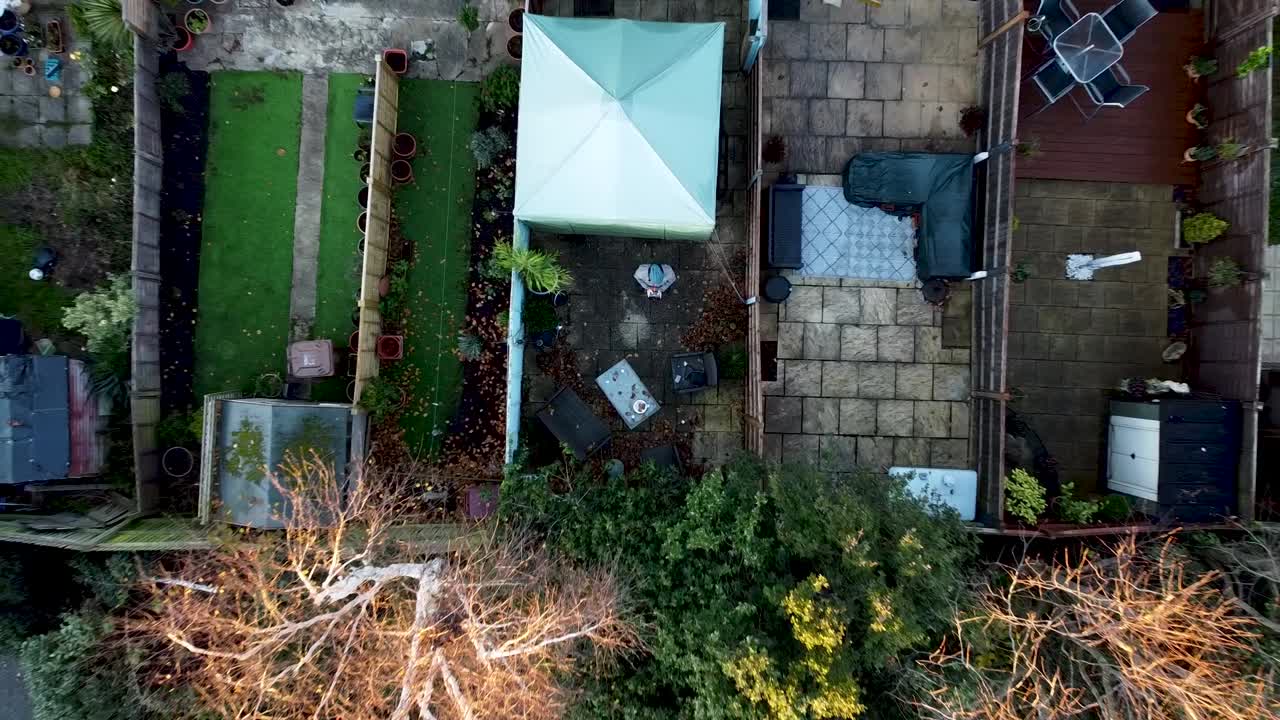 드론이 상승하고, 교외 지역의 개요 샷으로 이륙하고, 누군가 정원에서 드론 비행을 연습하고 있습니다.