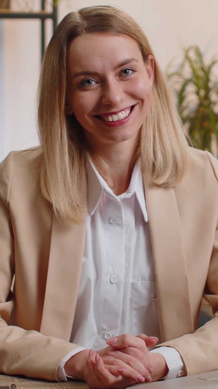 Ritratto di una felice donna d'affari bionda sorridente in ufficio a casa. Guarda lontano, gira la testa verso la telecamera.