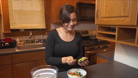 mujer joven en forma preparando ensalada saludable con verduras frescas y aguacate