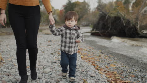 A-young-woman-leads-a-boy-by-the-hands-along-the-rocky-seashore