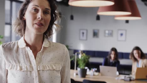 portrait of happy caucasian casual businesswoman using tablet in office with copy space, slow motion