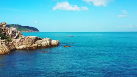 peaceful seascape with blue azure sea under bright sky with white clouds on rocky coastline of tropical island