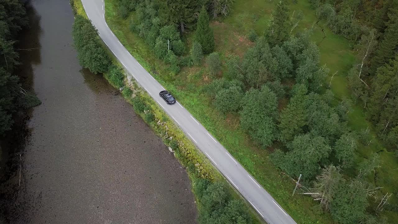 강가의 산골짜기를 달리는 테슬라 모델의 항공 영상