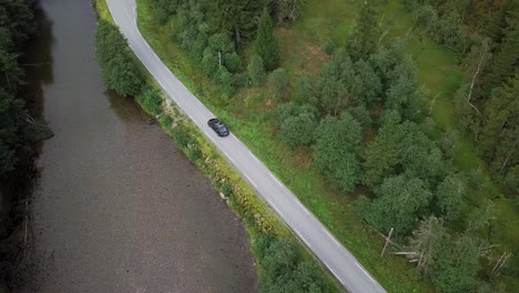 Luftvideo-Von-Tesla-Modellen,-Die-In-Einem-Bergtal-An-Einem-Fluss-Fahren