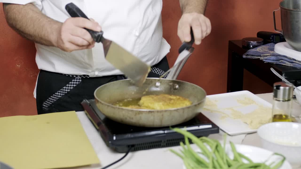 el chef está preparando la cotoletta alla milanese, un plato clásico italiano de carne, primo mediterráneo.
