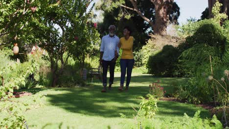 Glückliches-Afroamerikanisches-Paar-Hält-Händchen-Und-Geht-Im-Sonnigen-Garten-Spazieren