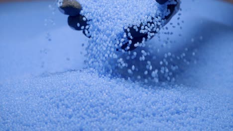 person wearing gloves holding up recycled blue plastic grains