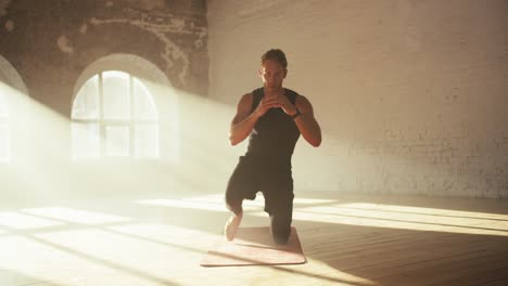 a male athlete in a black summer sports uniform kneels and then gets up. these are special exercises for pumping leg muscles