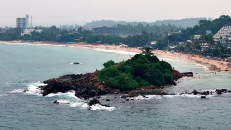 parrot rock islet, mirissa, sri lanka aerial high-angle view from standard telephoto lens, on hazy day, contrasts busy beach town backdrop