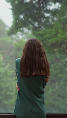 woman stands in self embrace against window. woman executive reflects on unrealized potential for company advancement with thoughts clouded by disappointment