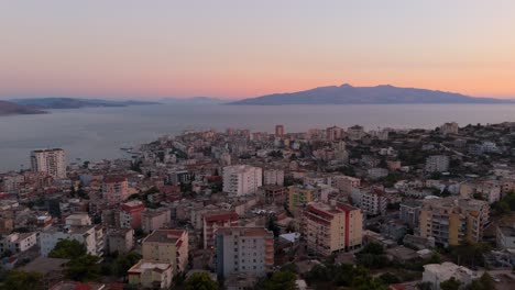 saranda, albania, con el paisaje de la ciudad costera y el mar al atardecer con la montaña en la distancia, vista aérea