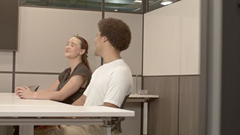 african american male in his 20's and a caucasian female in her 20's talking in business meeting with video moving right to left with door in foreground.