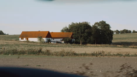 vistas en un viaje por carretera en el sur de suecia vacaciones en una pequeña granja con edificios blancos clásicos y techos naranjas rodeados de cultivos agrícolas agricultura vista desde el interior de un camión en una carretera