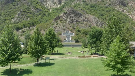 durchfliegen und eine leicht geneigte drohnenaufnahme einer kreuzskulptur, die zu gedenken an die opfer des vulkanausbruchs des kozuh-gebirges in der stadt rupite, petrich, bulgarien, gebaut wurde