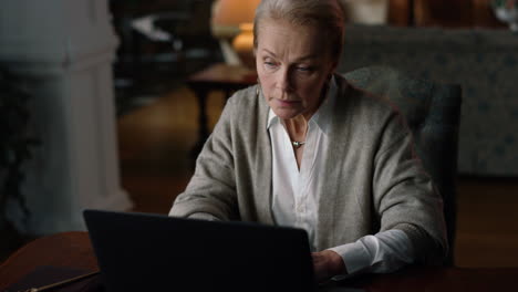 Rich business woman having video call vintage home. Senior lady working computer