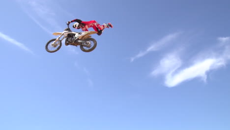 a motocross rider lands a trick over a big dirt jump