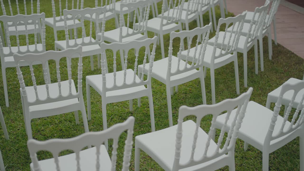 Neatly arranged white chairs set up on grass for outdoor wedding ceremony