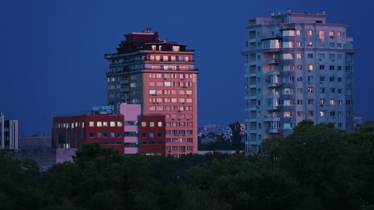 High rise apartments glow under the blue evening sky with lightning