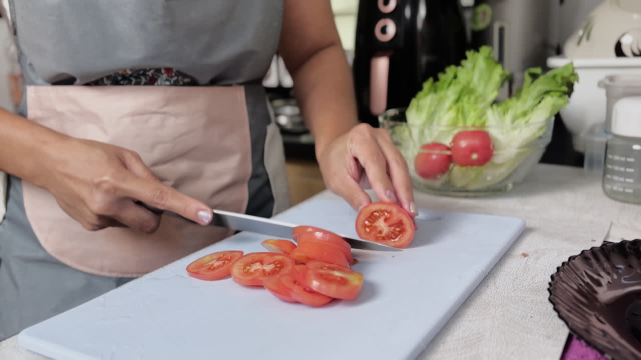 Tagliare pomodoro fresco su tagliere in cucina. Preparare verdure per l'insalata, cucina sana e processo di preparazione dei pasti.