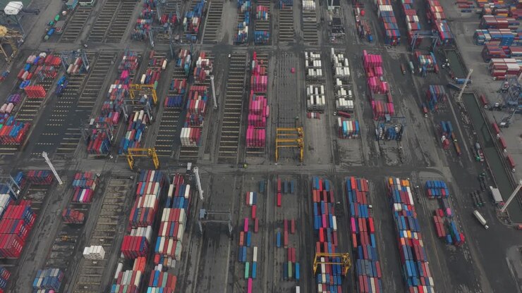 Top-down aerial view of shipping containers stacked at a port terminal in Jakarta, showing organized container storage and logistics patterns